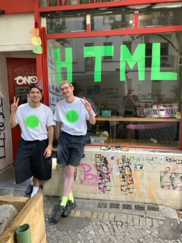 HTML in big green letters with organizers leaning against the building wall