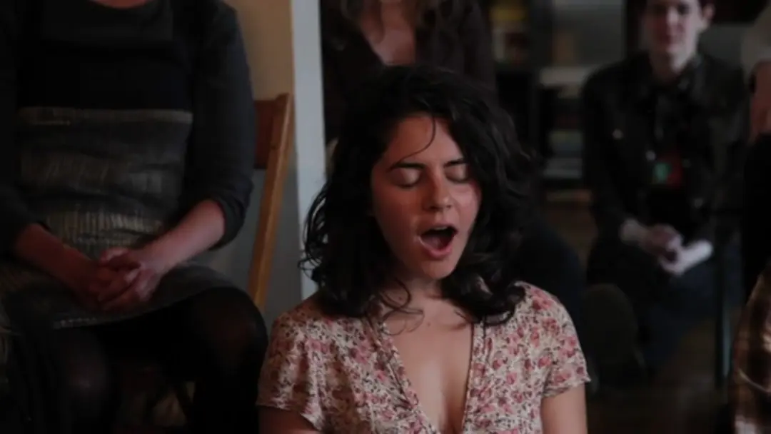 A woman with eyes closed shouts.