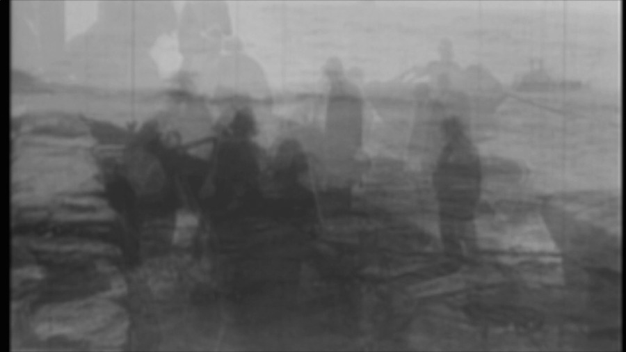 Screenshot of the video Distances with murky black and white image of people standing in open water
