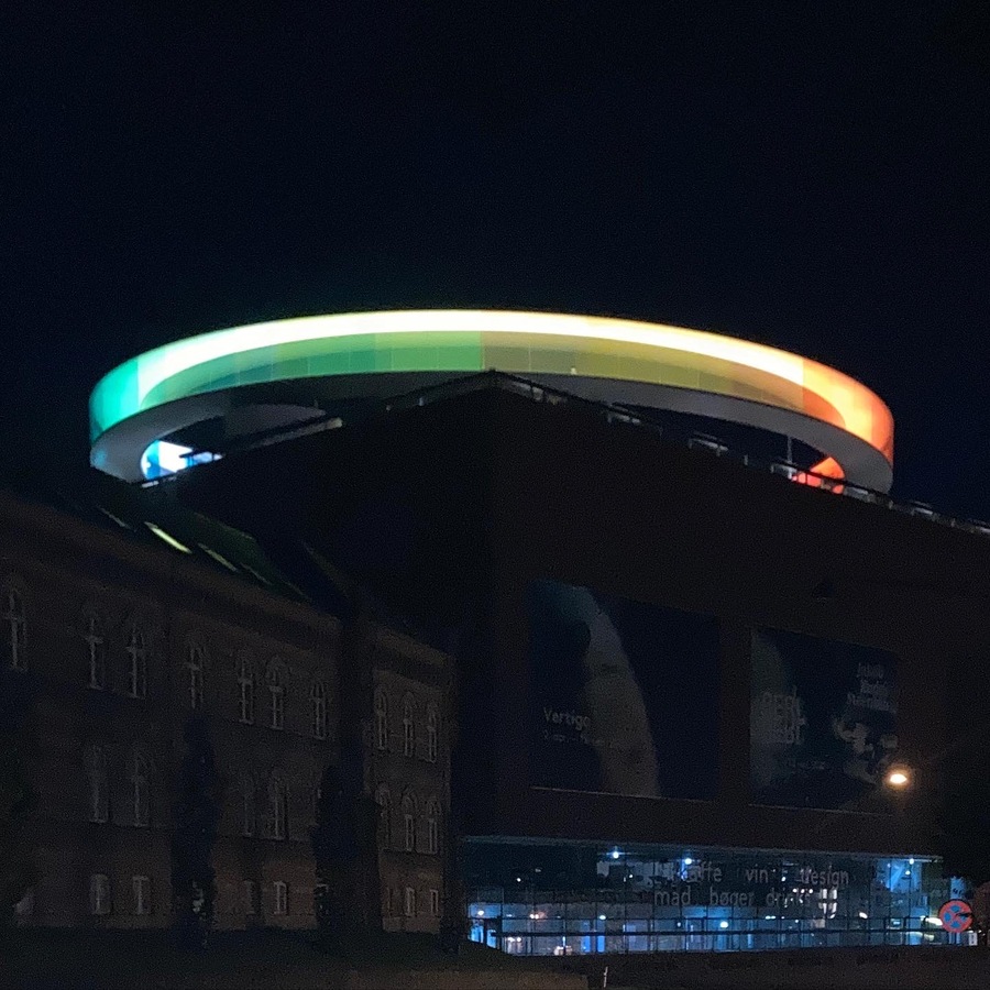 photograph of ARoS museum at night in the dark with glowing rainbow panorama hallway on top of the museum