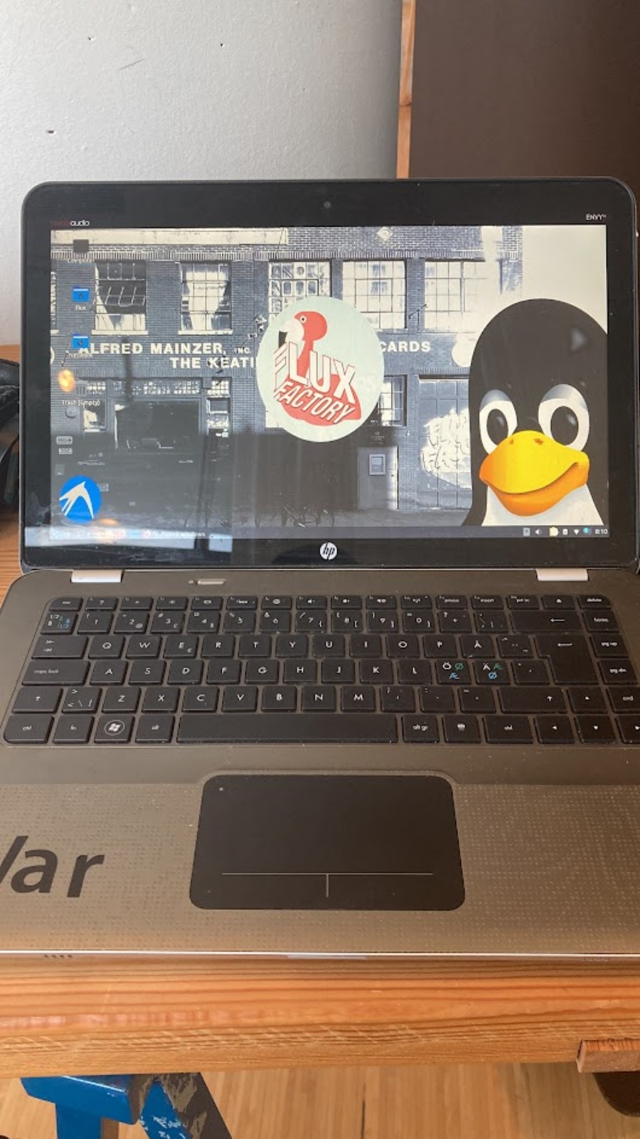 old laptop with Linux installed with a background image of Flux Factory with a penguin logo