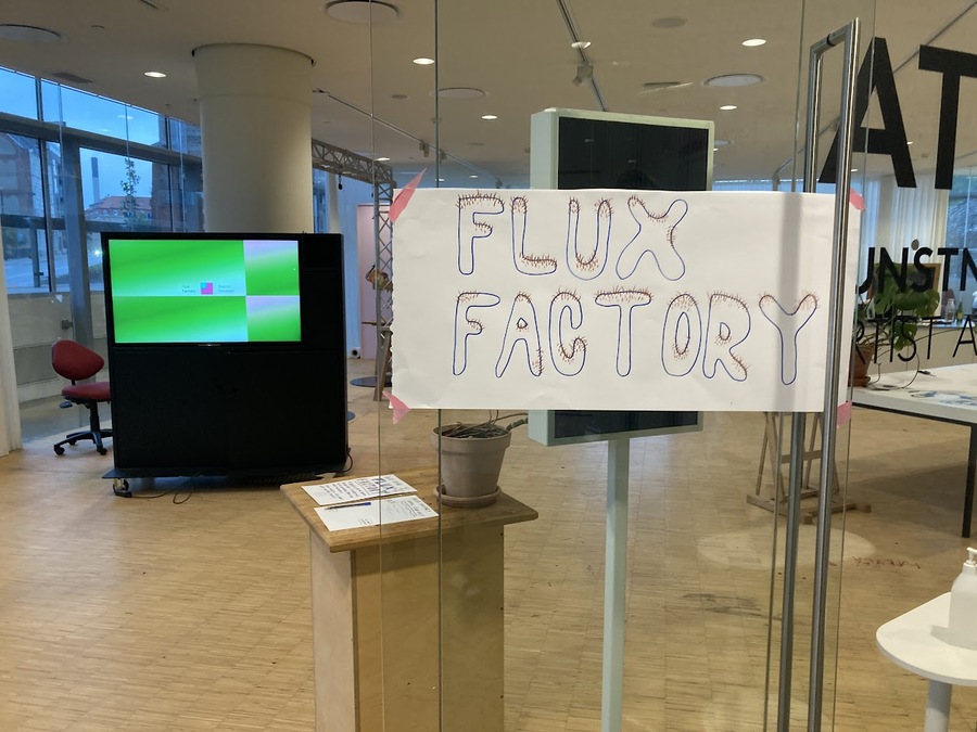 image of the studio in glassed-in area with hand-drawn poster for Flux Factory with hairy bubble letters