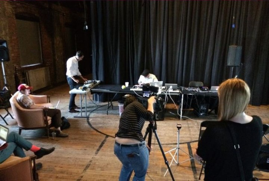 Studio view of SLOW FM showing camera person in center filming the scene.