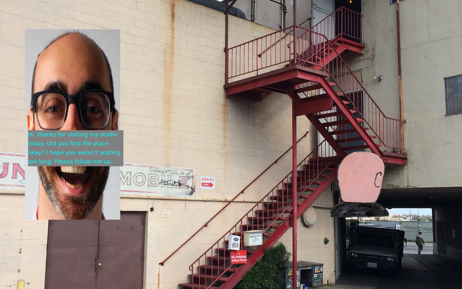 Lee's big head with text on top of it, floating in front of an industrial building with red stairs in Chinatown, LA. A small pink back of a person's head (Guston) on the right side.
